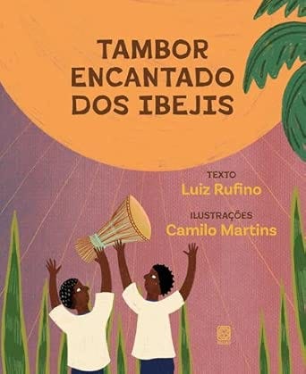 #descrevemospravocê  Capa do livro infantil Tambor Encantado dos Ibejis, com texto de Luiz Rufino e ilustrações de Camilo Martins. O fundo é composto por tons quentes de laranja, roxo e rosa, formando um céu ao entardecer com linhas diagonais sugerindo luz ou movimento. O título está centralizado na parte superior, em letras maiúsculas pretas. Abaixo, em letras menores, os créditos: “Texto Luiz Rufino” em amarelo e “Ilustrações Camilo Martins” em lilás.  Na parte inferior da imagem, duas crianças negras com cabelos crespos e curtos aparecem de frente, levantando um grande tambor entre as mãos. Ambas usam camisetas brancas; uma veste uma saia azul e a outra, um short azul. As crianças estão sorrindo e olham para o tambor, que tem tons de bege e detalhes em verde. Elas estão cercadas por folhas alongadas de bananeira que brotam do chão, reforçando o cenário natural. No canto superior direito, parte de uma grande bananeira aparece, com folhas largas e verdes, destacando-se contra o céu colorido. A ilustração tem traços simples e cores vivas, com estética inspirada em elementos da cultura afro-brasileira.