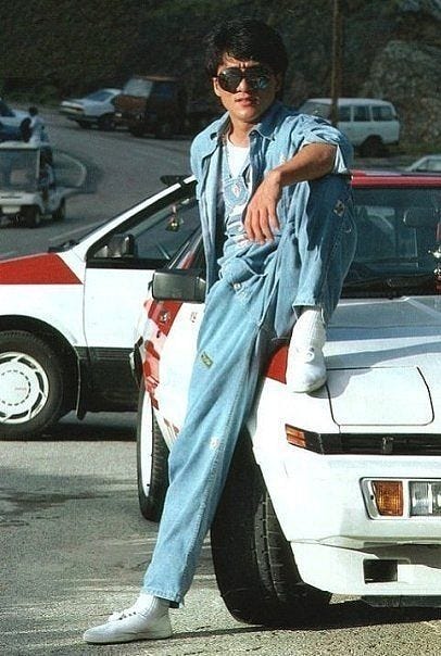 This may contain: a man leaning on the hood of a car
