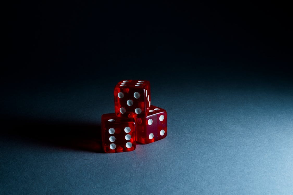 Free Three red transparent dice stacked on a dark surface, highlighting their reflective surfaces and dots. Stock Photo