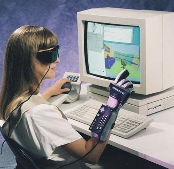 A person working at a CRT workstation with a visor and a hand-mounted controller.