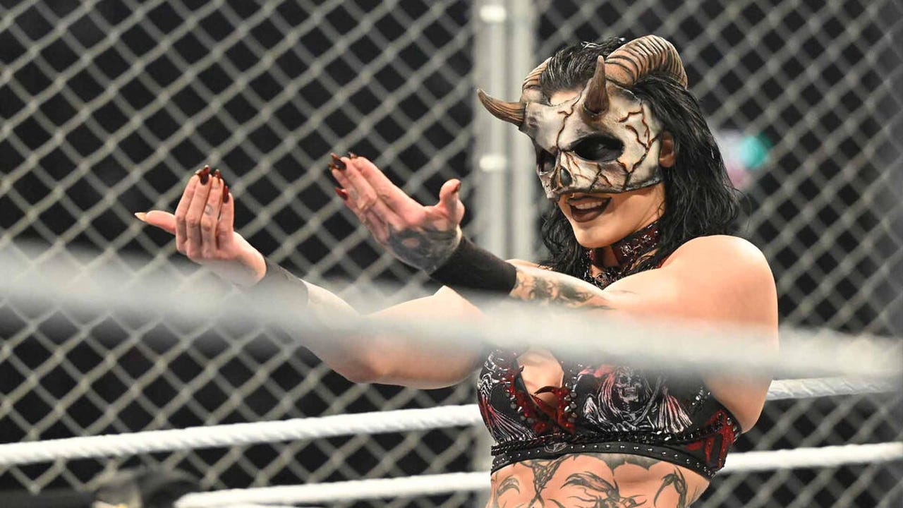 A imagem mostra Rhea Ripley, uma lutadora profissional australiana da WWE, usando uma máscara com chifres e um traje de luta temático. Esta máscara foi criada pelo artista de efeitos especiais de terror Jason Baker para a sua aparição no evento Survivor Series: WarGames. 