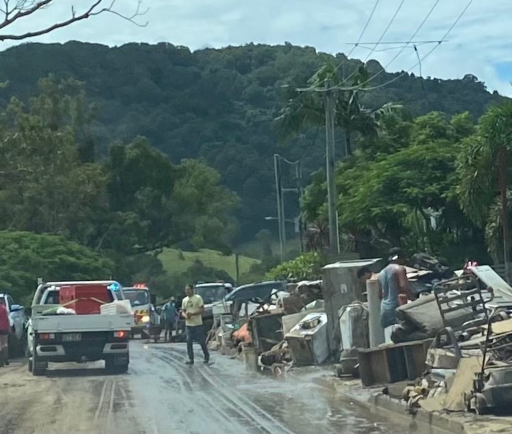 Flood-ruined possessions line a muddy street awaiting removal