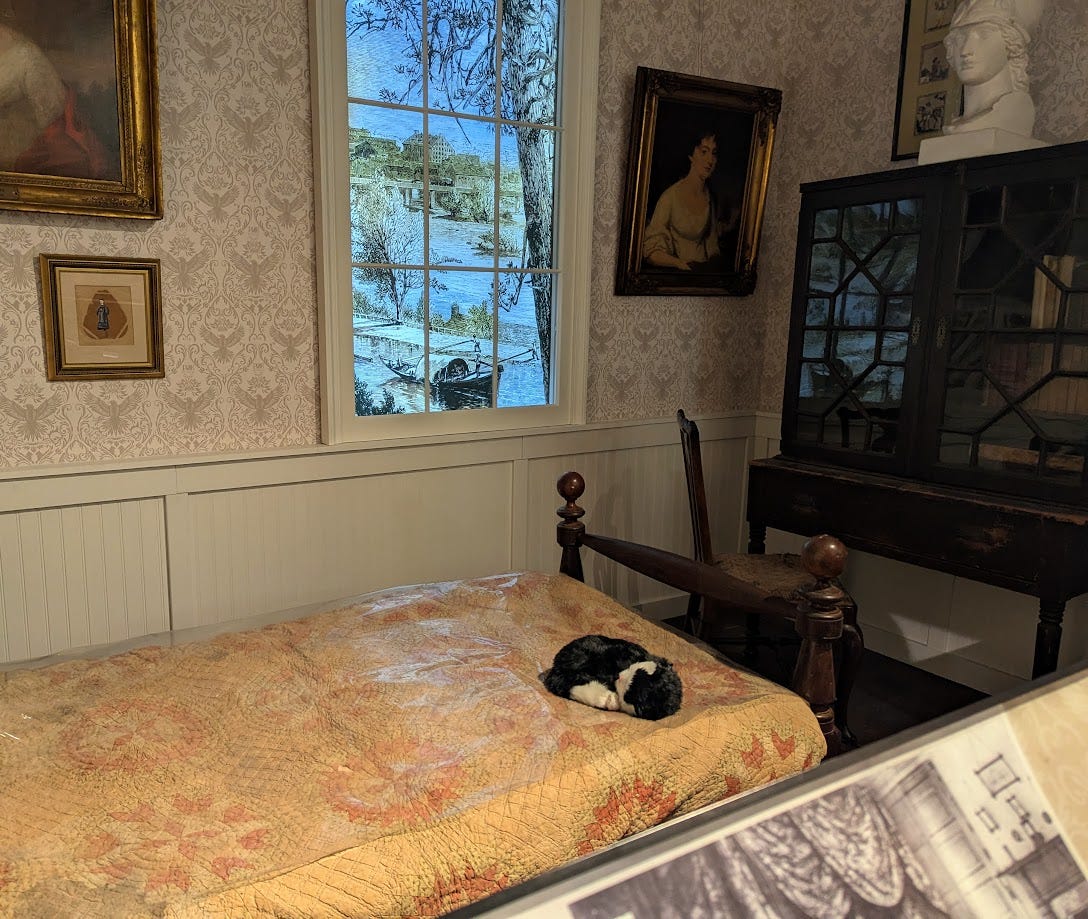 Edgar Allan Poe's childhood bed with a stuffed cat on it at the Poe Museum
