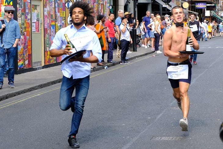 Two waiters running to the finish line - one is topless Two waiters running to the finish line - one is topless