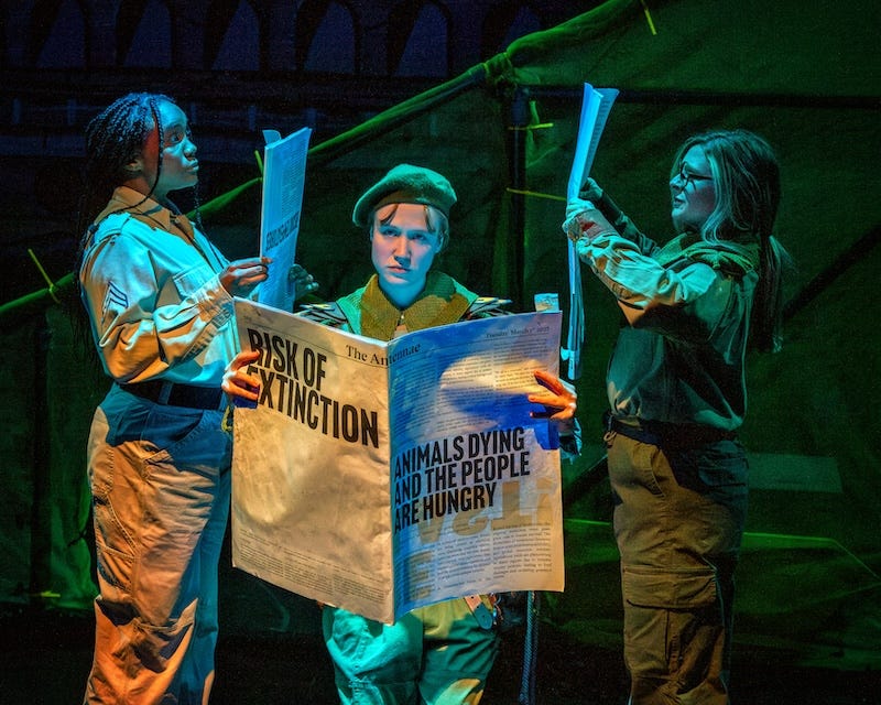 A photo shows three performers reading newspapers, the headline reads 'risk of extinction'