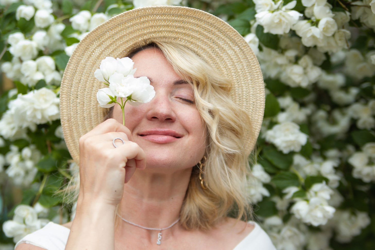 Woman being straw hat eyes closed white flower in front of face Woman being straw hat eyes closed white flower in front of face