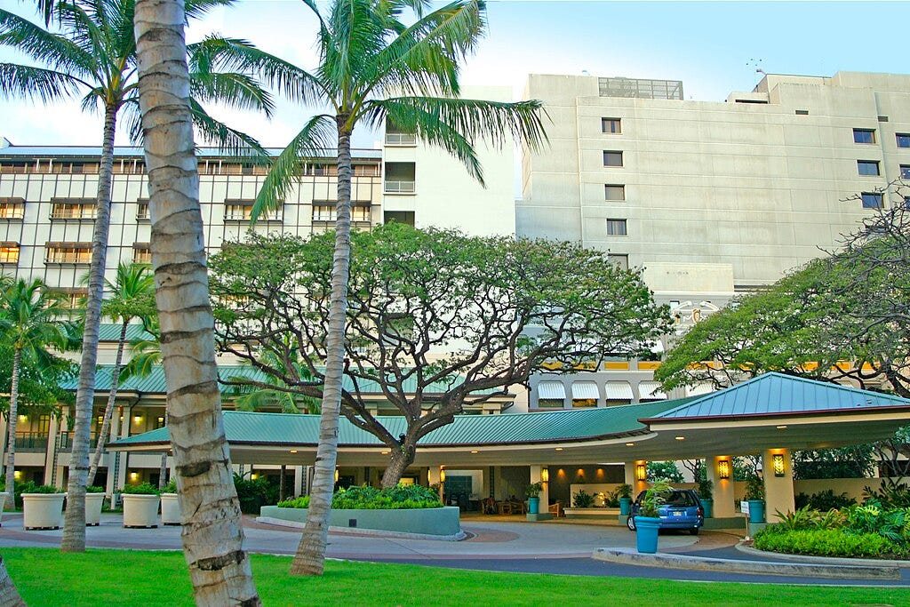The front entrance of a hospital with tropical trees