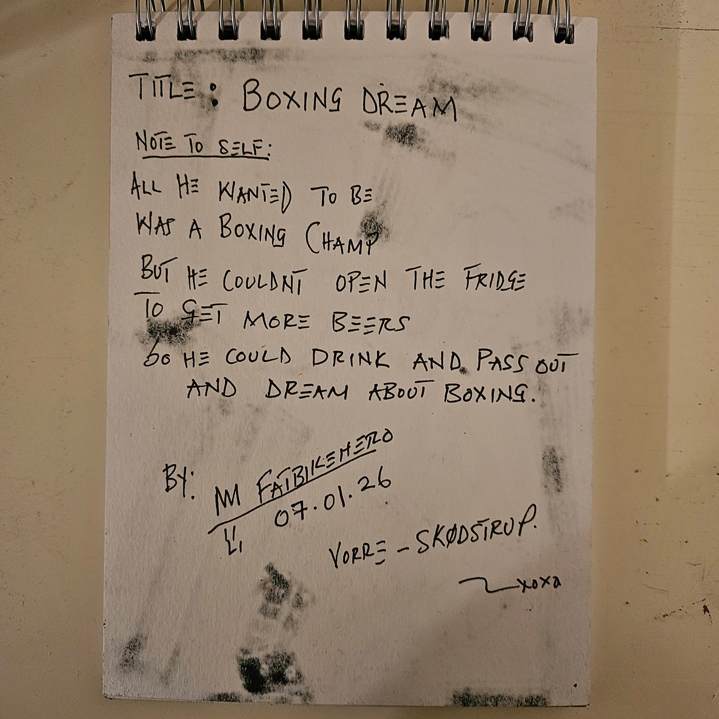 A photograph of a sketchbook page with handwritten text in black ink. The header reads "Title: BOXING DREAM." The "Note to self" below describes a tragic narrative: "All he wanted to be was a boxing champ but he couldnt open the fridge to get more beers so he could drink and pass out and dream about boxing." The page is signed "By: M FatbikeHero," dated "07.01.26," and located in "Vorre - Skødstrup."