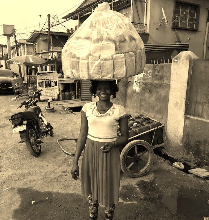 This may contain: a woman is carrying bread on her head