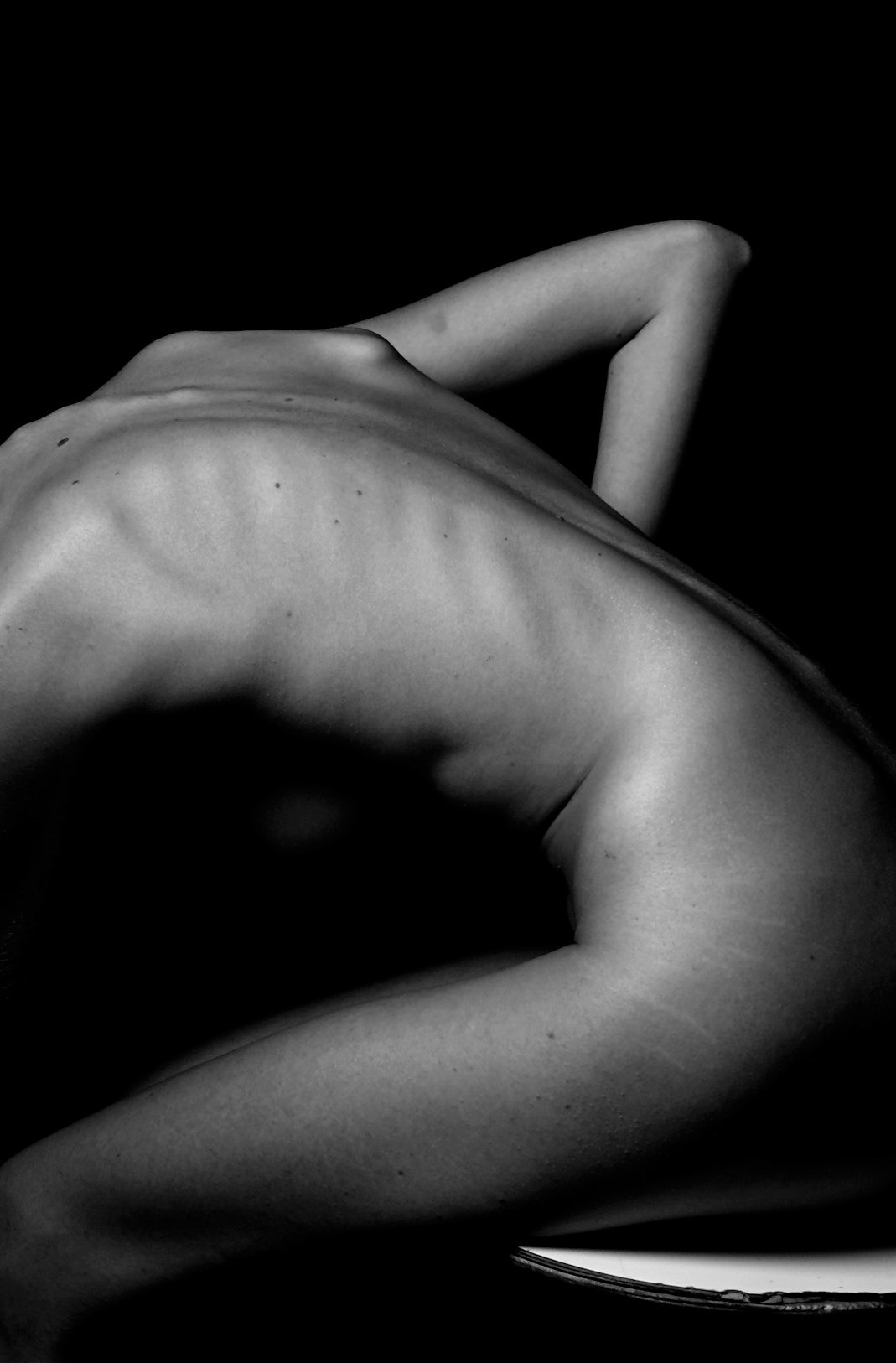 a naked woman sitting on a table with her back to the camera