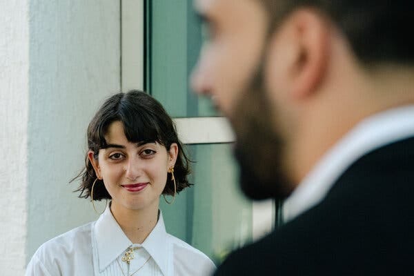 Rama Duwaji, wearing a white shirt and large hoop earrings, smiles at Zohran Mamdani, who is blurred in the foreground. Rama Duwaji, wearing a white shirt and large hoop earrings, smiles at Zohran Mamdani, who is blurred in the foreground.