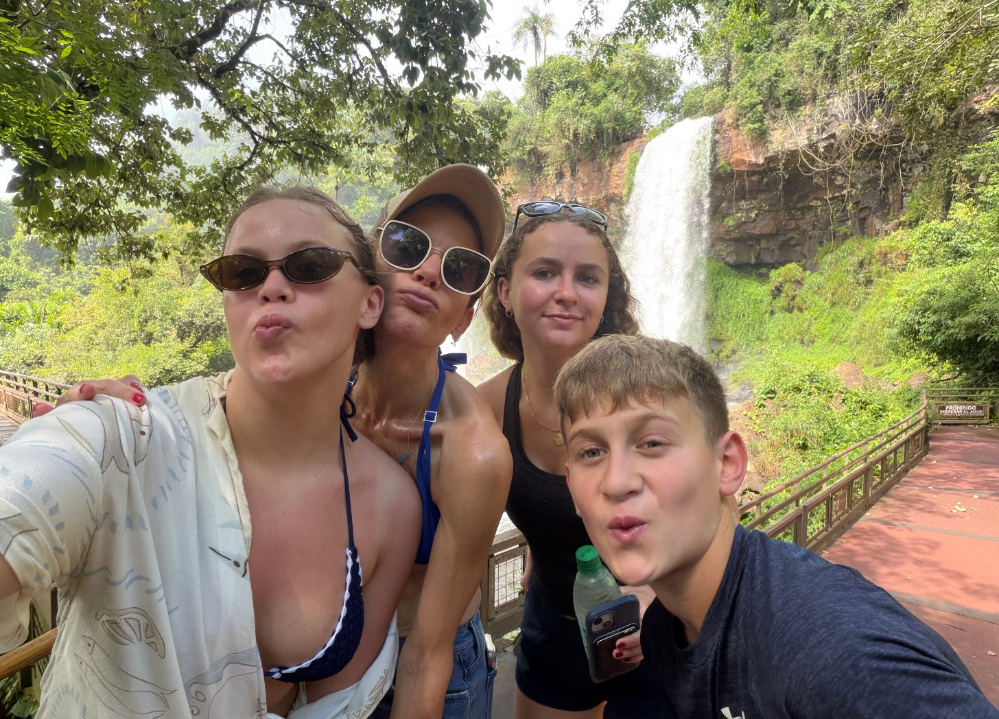 Photo of a mom with three kids posed in front of a waterfall