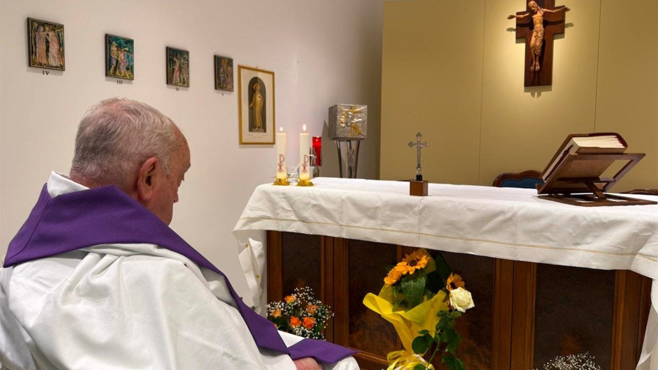 Pope Francis, seen from behind in an alb and purple stole, sits before the altar of the Gemelli Hospital chapel