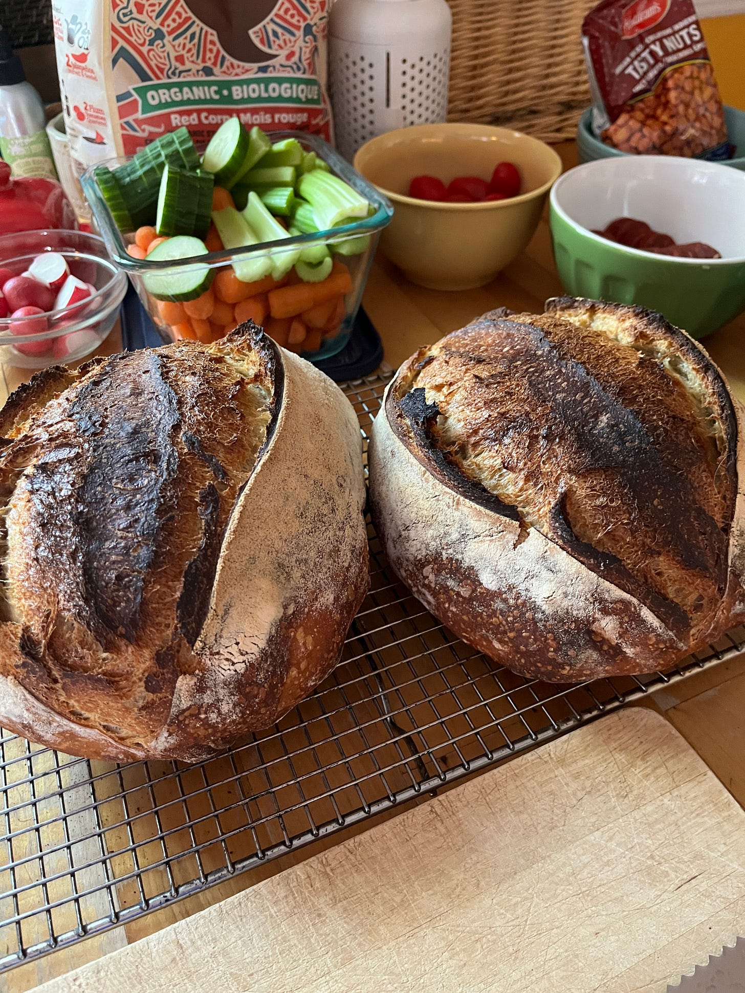 My kithcn countertop with a couple of nice loaves of sourdough bread and various bowls of veggies and snacks