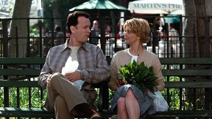 This may contain: a man and woman sitting on a park bench with flowers in their hands, looking at each other