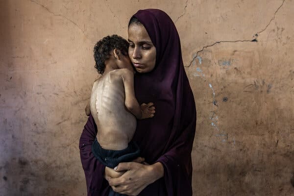 A mother holds an emaciated child.