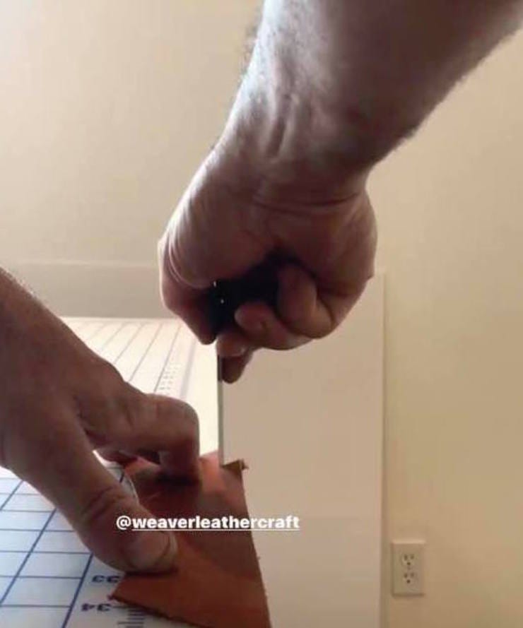 Cutting leather on the edge of a table.