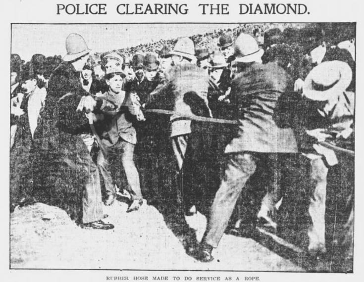 Photograph of police shifting a crowd with a piece of rubber hose. Photograph of police shifting a crowd with a piece of rubber hose.