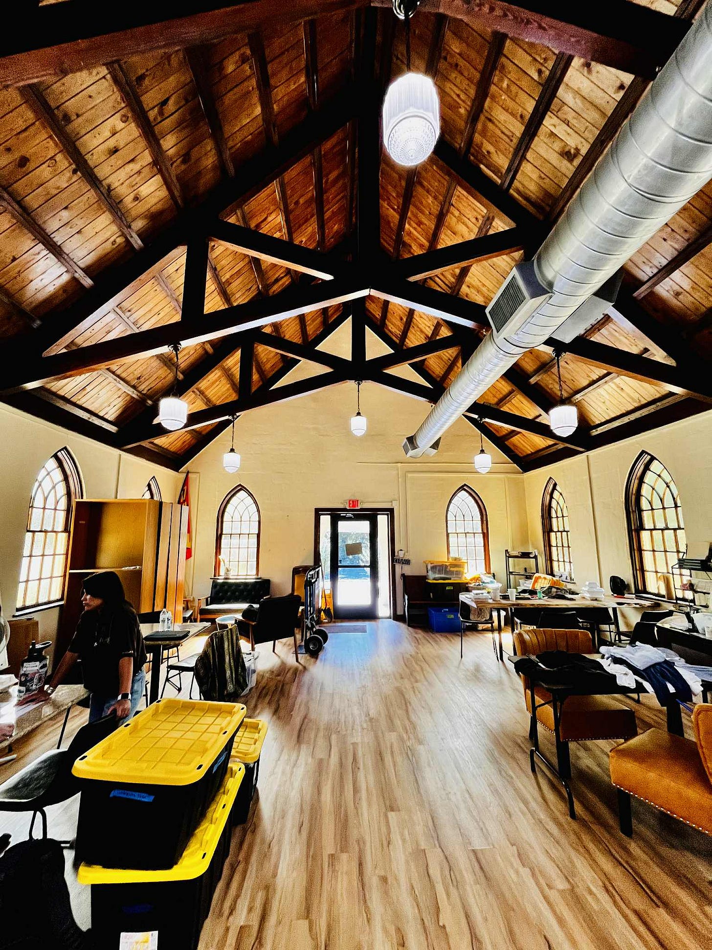 Interior of the Titled Map, a large room with high vaulted ceilings shows team members with storage boxes settling into the building.