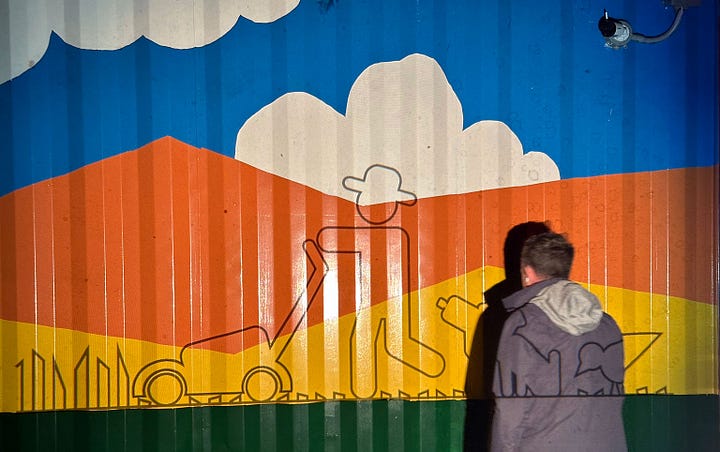 Photo gallery of process shots of the painting of The Lawn Mower Mural on the side of a shipping container cabin.