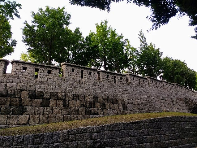 A stone wall with trees in the background

AI-generated content may be incorrect.