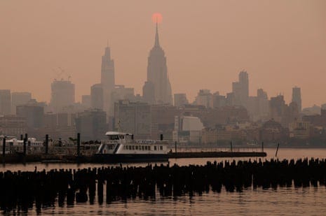 The sun is shrouded as it rises in a hazy, smoky sky behind the Empire State Building in New York City on 6 June.