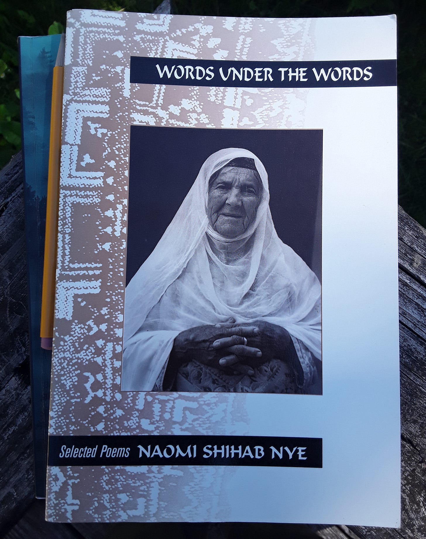 Photo of a notebook, pencil and the book Words Under the Words by Naomi Shihab Nye