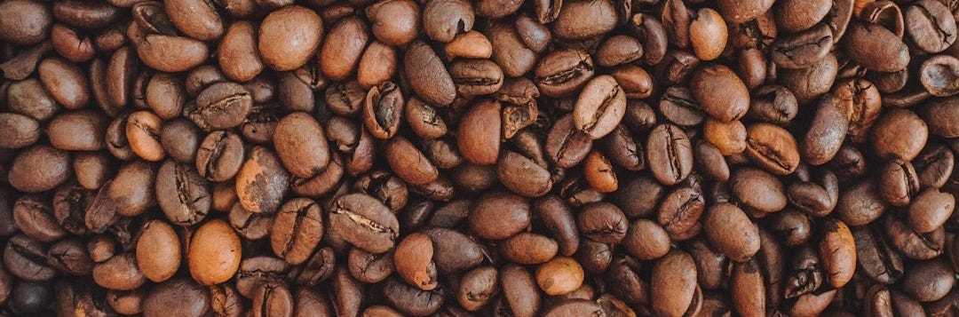 brown coffee beans on brown wooden table brown coffee beans on brown wooden table
