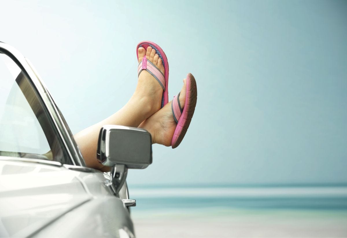 Car at beach, crossed feet sticking up out of it