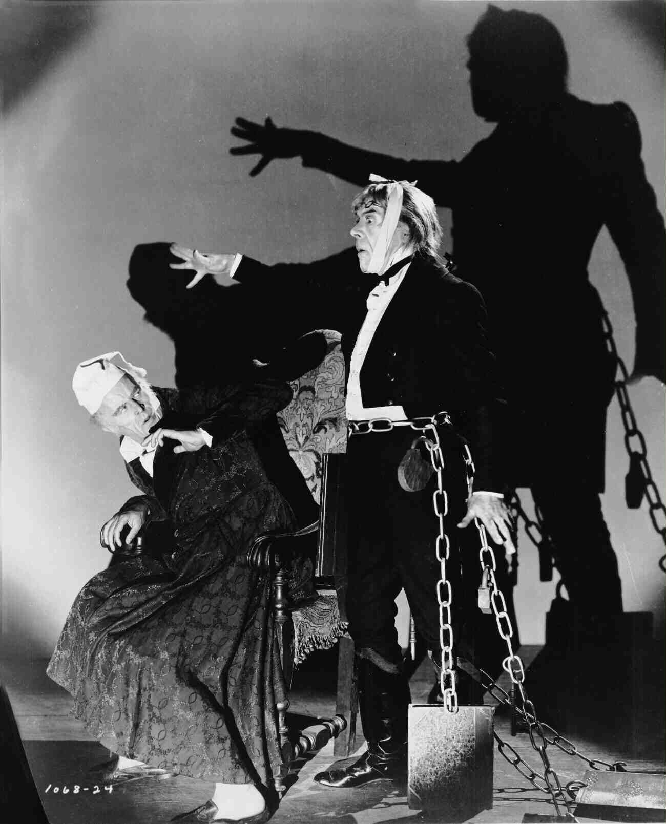 Full publicity shot of Reginald Owen as Ebenezer Scrooge, seated ...