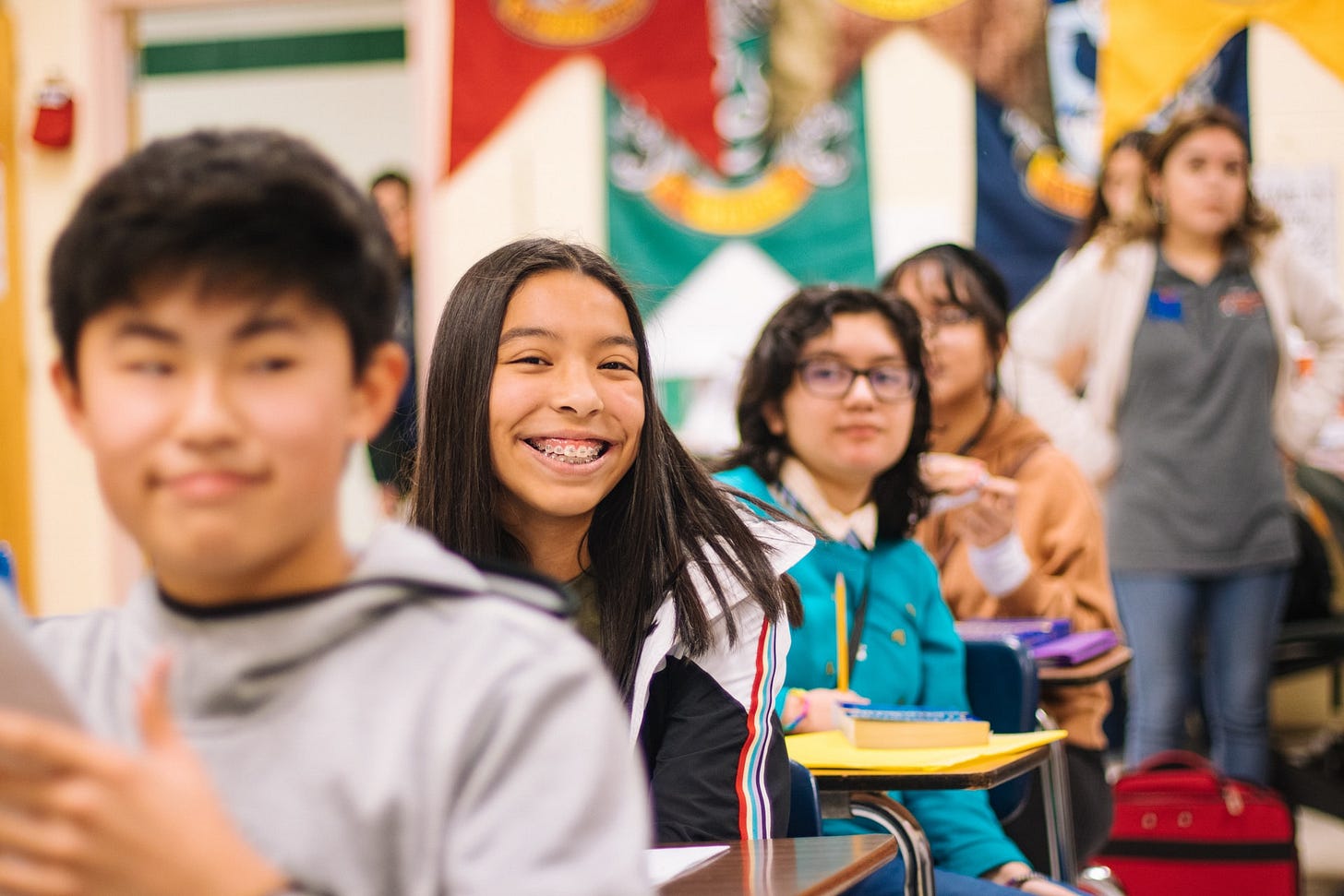 smiling girl with braces sitting in her classroom with other students smiling girl with braces sitting in her classroom with other students