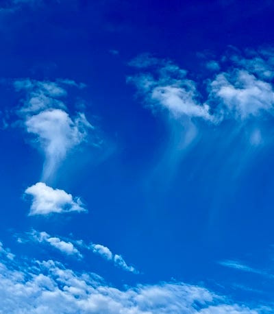 White jellyfish-like clouds float in a cerulean sea of sky.