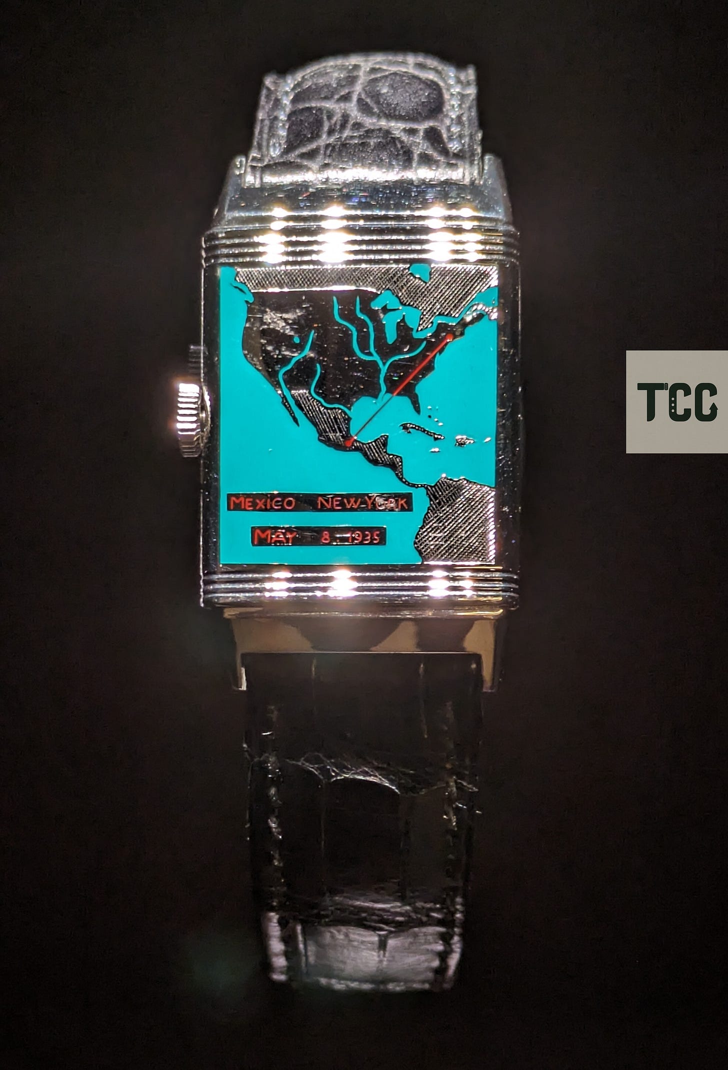 Close-up of a turquoise Reverso dial featuring a cloisonné map connecting Mexico and New York with a red flight path.
