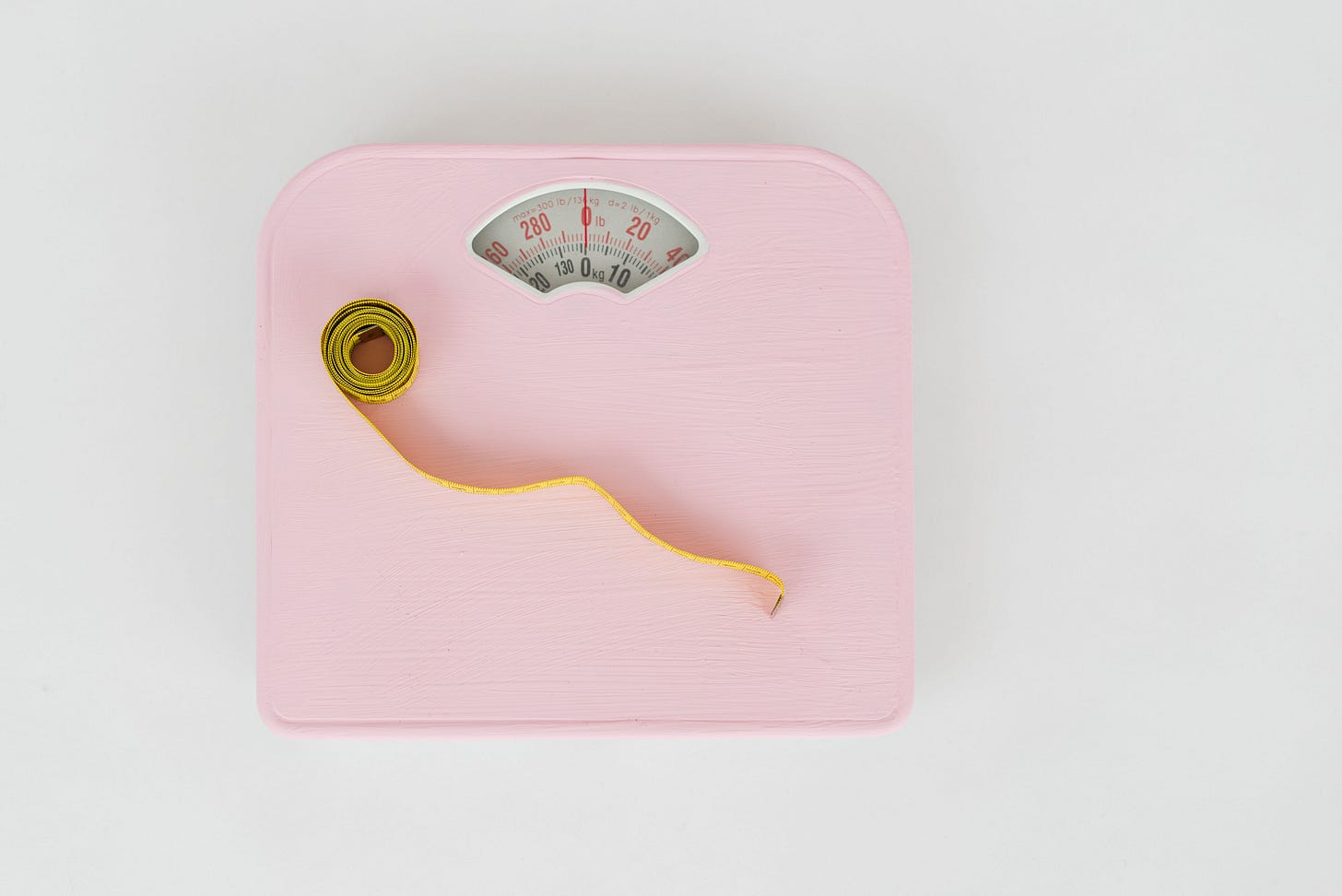 Image of a pink weighing scale and tape measure