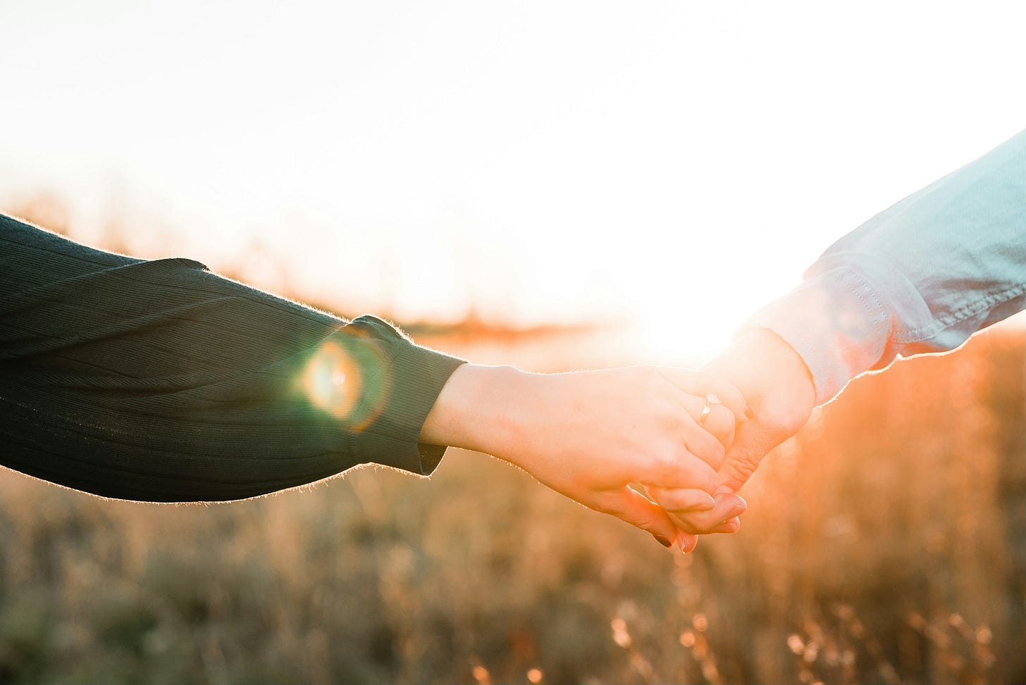 a couple holding hands in a field