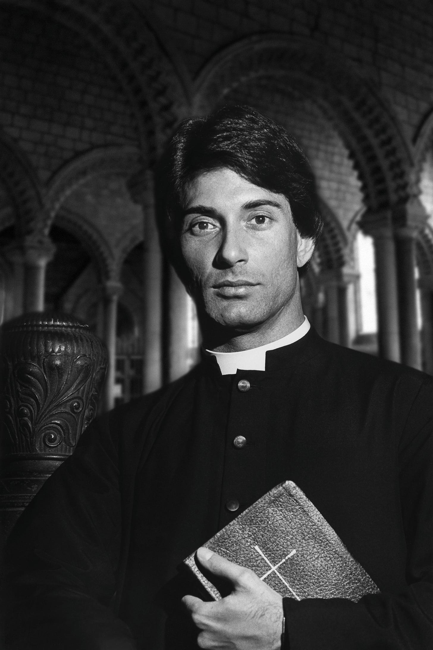 Young priest in a cathedral, holding a Bible