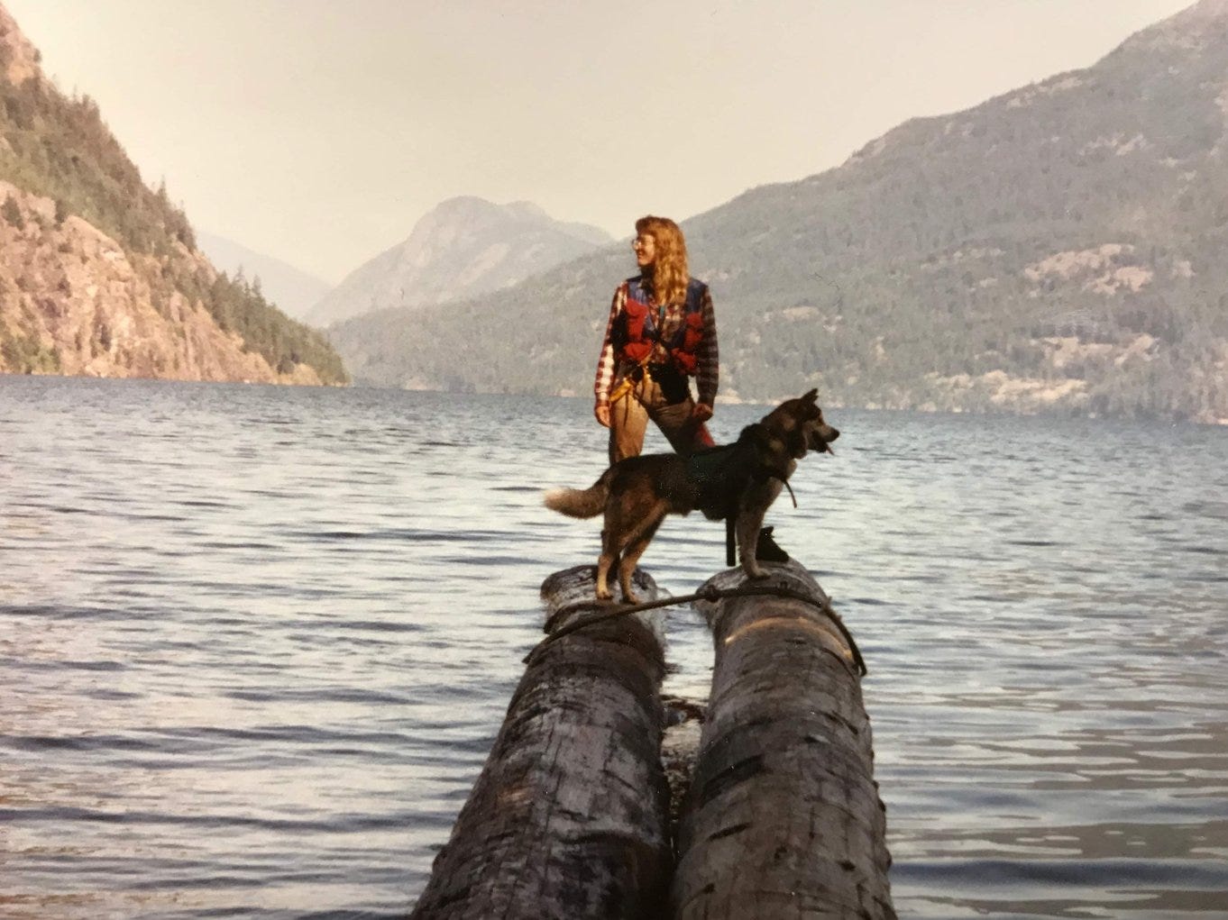 michele peters standing on log in water with black dog Nitro in North Cascades Wilderness Area michele peters standing on log in water with black dog Nitro in North Cascades Wilderness Area