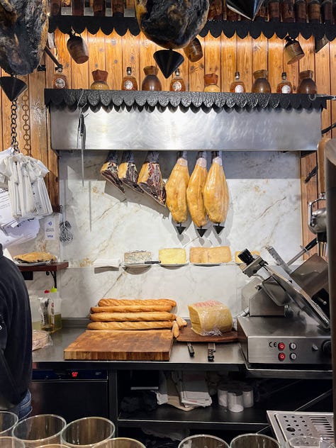 anchovies and blue cheese on a bed of fried onion, a bar meat station with hanging jamon and wrapped cheese, pickled peppers, olives and anchovies on a toothpick