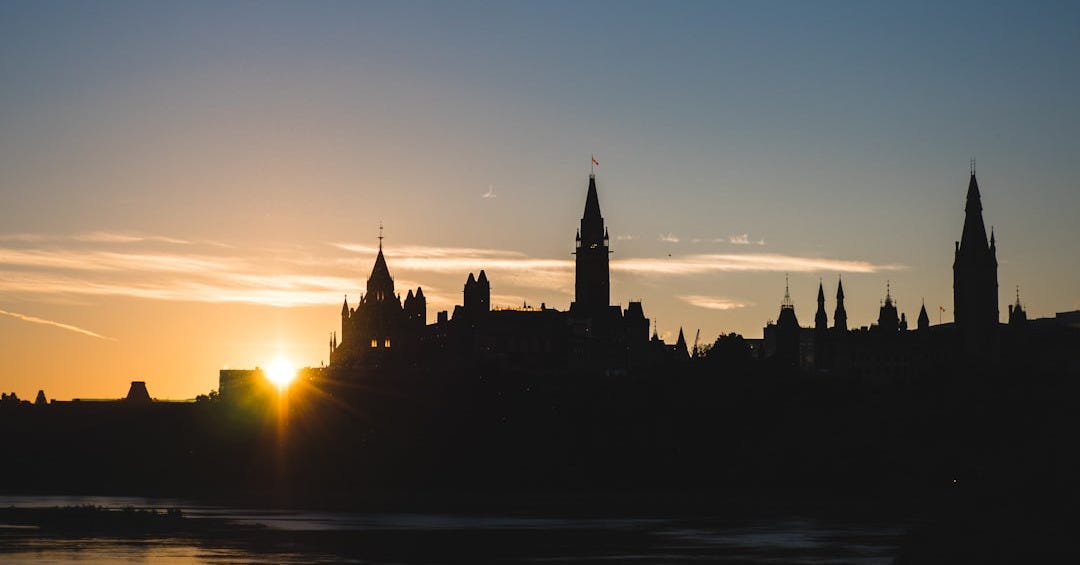 silhouette of houses and tower near river during sunrise