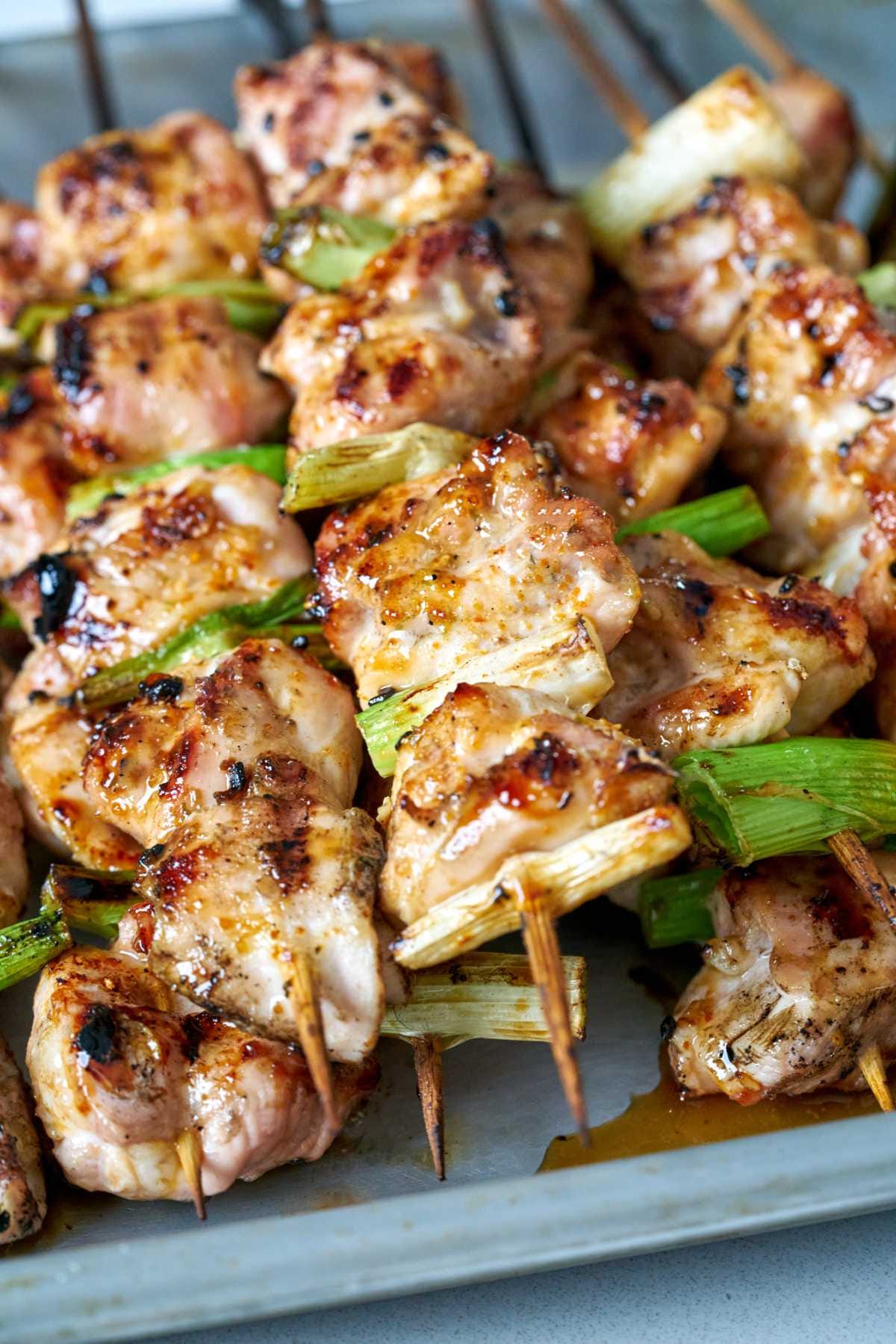 Several stacked chicken kabobs on skewers with green scallions. Several stacked chicken kabobs on skewers with green scallions.