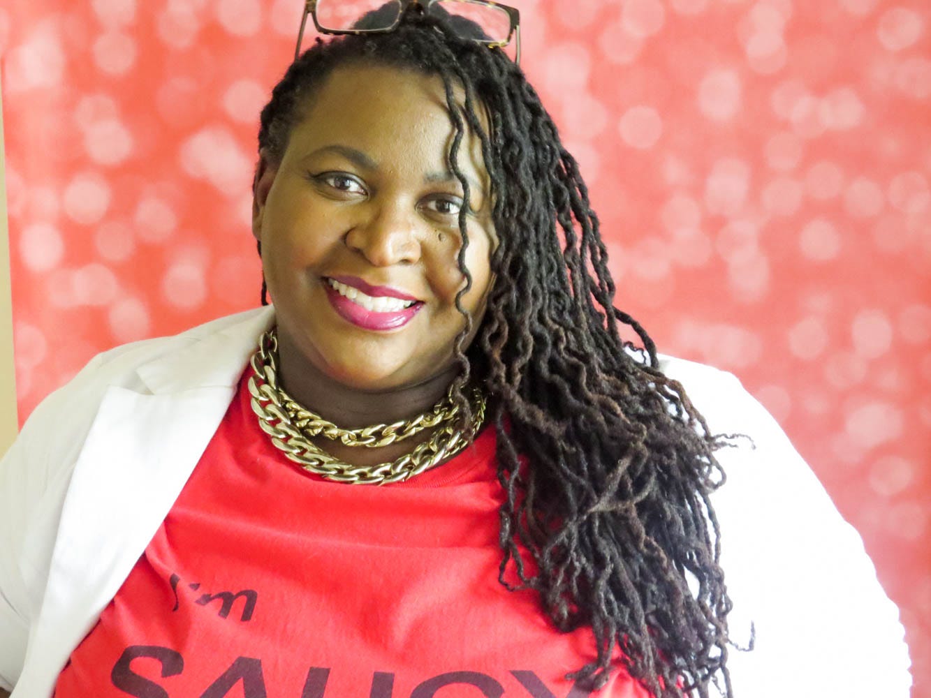 Demetra Overton looking at camera smiling in red shirt and white blazer