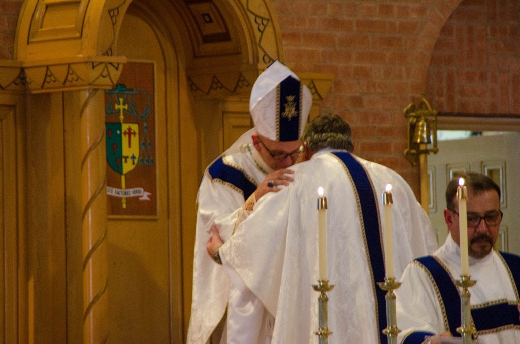 Bishop Wall embraces the newly-ordained priest. Bishop Wall embraces the newly-ordained priest.