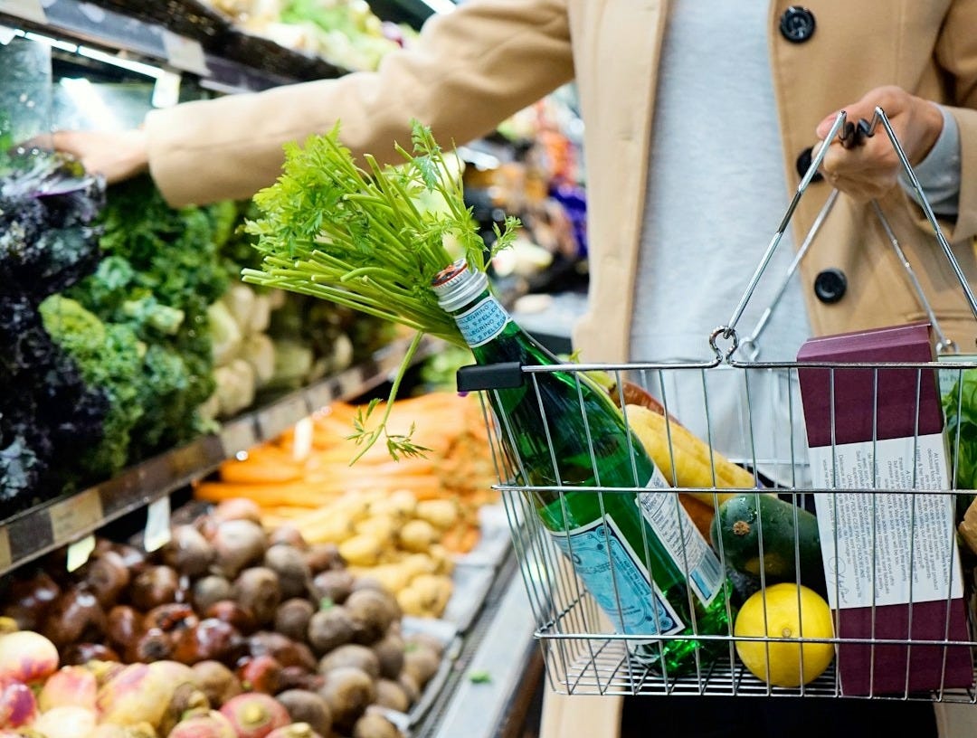woman in white coat holding green shopping cart woman in white coat holding green shopping cart
