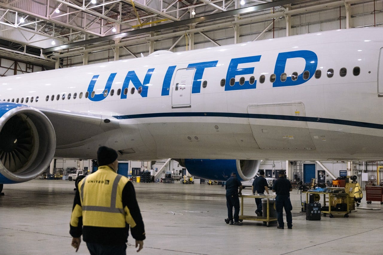 Workers replace an electrical cable on a Boeing 777-200 airplane in a United Airlines maintenance hangar at Newark Liberty International Airport in Newark, New Jersey.