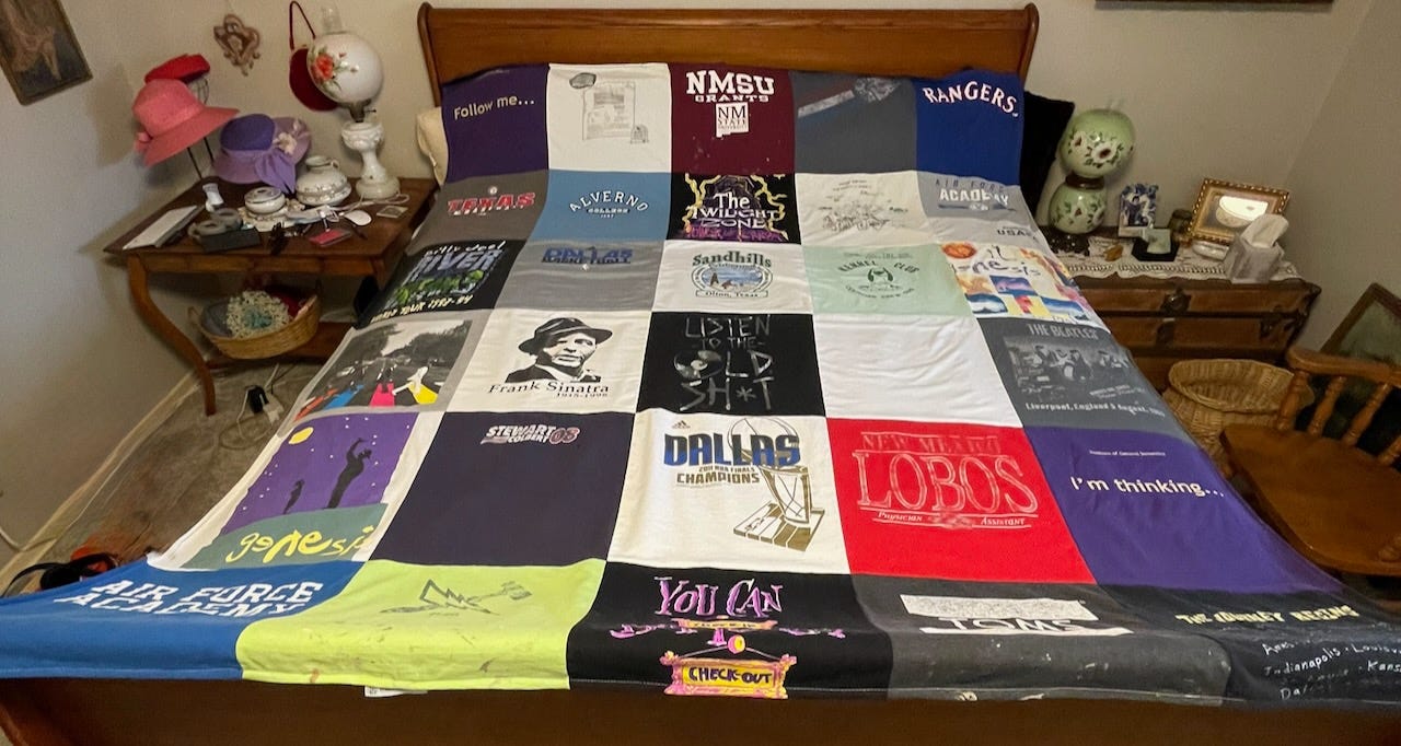 photo of a king-sized bed with a 30-panel t-shirt quilt lying atop