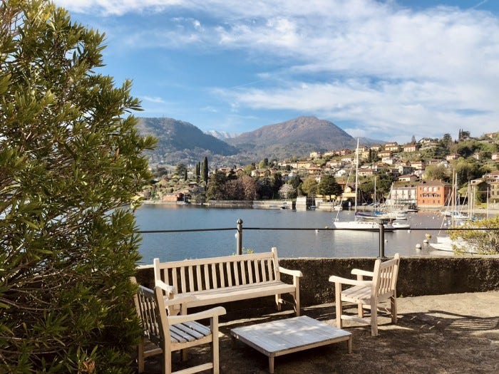 Benches and a small table at the side of the lake with mountains the in the background.