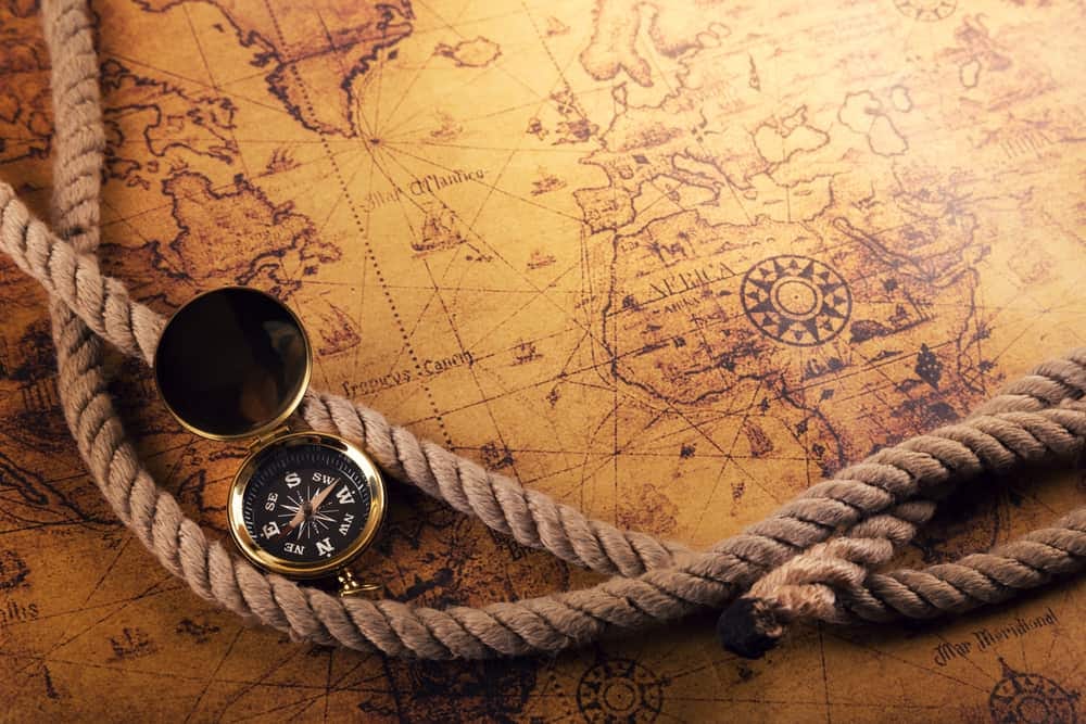Sepia-toned map of the Atlantic Ocean with Africa and Europe most visible. Ship's rope and a compass are on top of the map. Sepia-toned map of the Atlantic Ocean with Africa and Europe most visible. Ship's rope and a compass are on top of the map.