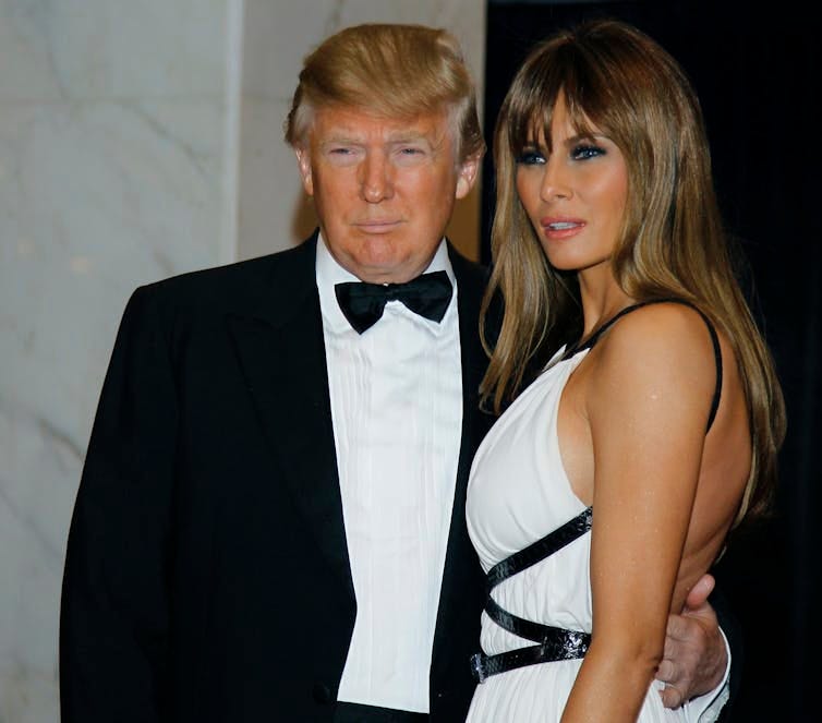 A man in a tuxedo and woman in a dress pose for photos.