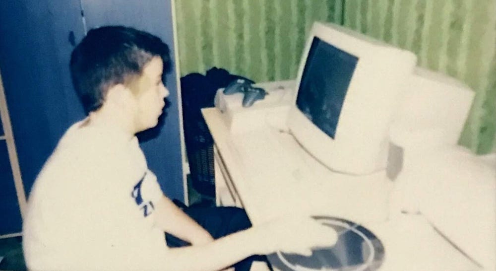 Dean as a child sitting at a desk using a computer