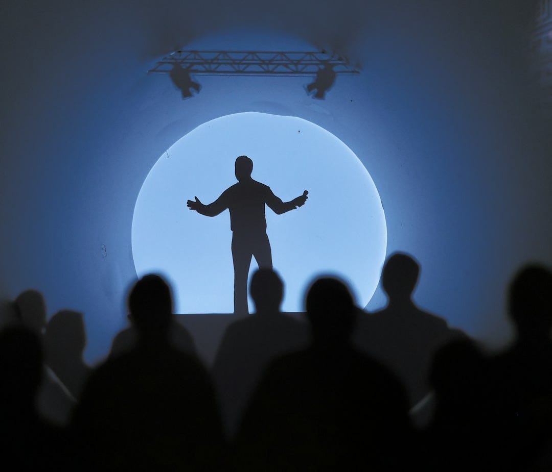 a silhouette of a man standing in front of a crowd a silhouette of a man standing in front of a crowd